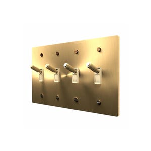 May include: A rectangular brushed brass wall plate featuring four toggle light switches. Each switch has a textured, knurled cylindrical handle and is secured to the plate with matching brass screws at the top and bottom corners.