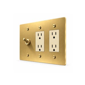 May include: A rectangular brushed brass wall plate featuring one toggle light switch and two duplex electrical outlets. The plate is secured with six matching brass screws, providing a metallic finish to the electrical fixture.