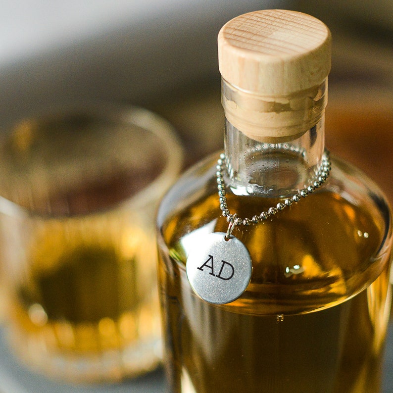 A personalised metal tag printed with initials hung around the neck of the glass decanter.