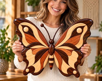 Puede incluir: Una pieza decorativa de pared con forma de mariposa, elaborada con diversas tonalidades de madera natural. La mariposa presenta segmentos de madera superpuestos en tonos marrón claro, medio y oscuro, creando un patrón de alas simétrico.