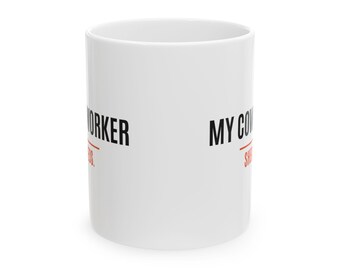 Può includere: Una tazza in ceramica bianca con testo nero che recita MY COWORKER e WORKER, con una linea orizzontale rossa sotto ogni parola. La tazza ha una forma cilindrica con una finitura liscia e lucida e un semplice manico.