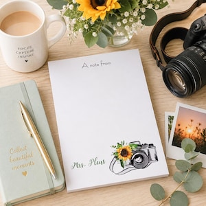 May include: A white notepad with the text "A note from" and "Mrs. Pleus" in script. A floral camera illustration with a sunflower is on the bottom right. A mug with coffee and the words "Focus Capture Inspire" is on the left.