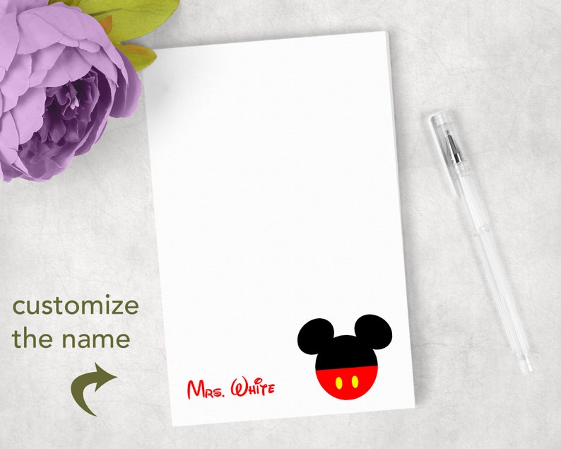 K&ouml;nnte beinhalten: Ein wei&szlig;er, rechteckiger Notizblock mit einer Grafik eines schwarz-roten Mauskopf-Symbols mit gelben Augen. Der Text "Mrs. White" ist unten links in Rot gedruckt. Der Text "customize the name" erscheint in Gr&uuml;n mit einem Pfeil.