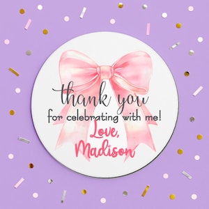 May include: Round white thank you sticker with a pink watercolor bow. The text reads "Thank you for celebrating with me! Love, Madison".