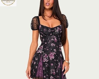 May include: A black mini dress featuring a floral pattern in shades of purple and pink. The garment has short puff sleeves made of black lace, a sweetheart neckline with a ruched bodice, and side panels of purple fabric under black lace.
