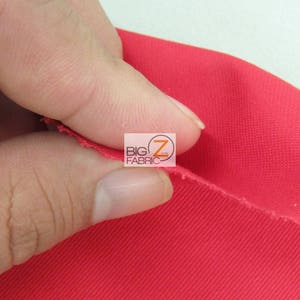 May include: Close-up of a bright red fabric with a textured weave. The fabric is being held in a hand, showing the texture and drape.