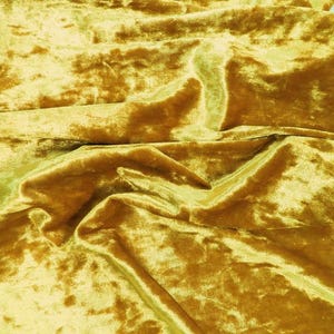 May include: A close-up of a crumpled piece of golden yellow velvet fabric. The fabric has a soft, luxurious texture.