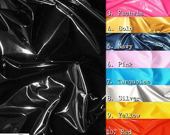 Op de afbeelding: Een close-up van een zwarte vinylstof met een glanzende, gladde afwerking. De afbeelding toont een verscheidenheid aan kleuren vinylstof, waaronder wit, fuchsia, goud, marineblauw, roze, turquoise, zilver, geel, rood en groen.