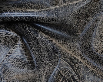 Op de afbeelding: Close-up van donkerbruin leer met een getextureerd, gebarsten oppervlak. Het leer heeft een natuurlijke, rustieke uitstraling.