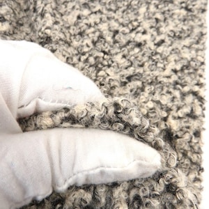 May include: Close-up of a black and white fuzzy fabric. The fabric has a soft, textured appearance.