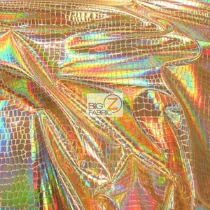 May include: Gold iridescent fabric with a crocodile skin pattern. The fabric has a shiny, holographic finish.