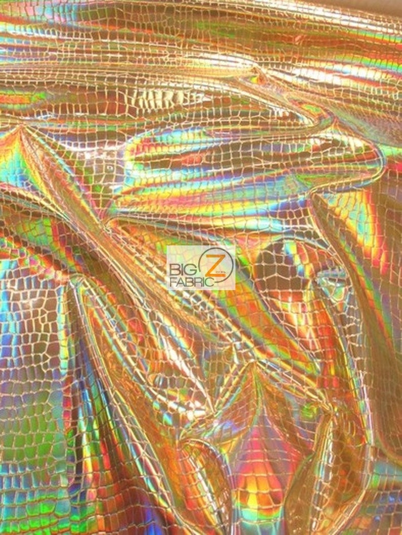 May include: Gold iridescent fabric with a crocodile skin pattern. The fabric has a shiny, holographic finish.