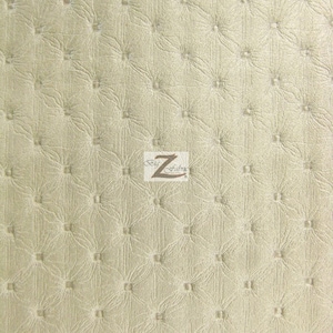 Puede incluir: Un primer plano de una tela beige con un patrón acolchado en forma de diamante. La tela tiene un brillo sutil y una superficie ligeramente texturizada. Una pequeña etiqueta blanca con el texto "Z Fabric" es visible en el centro de la imagen.
