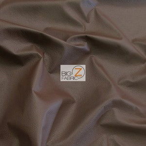 May include: Close-up of a brown faux leather fabric with a textured surface. The fabric is soft and supple, with a subtle sheen.