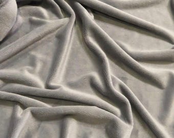 May include: A soft, gray fabric with a smooth, velvety texture. The fabric is draped and folded, creating a luxurious and cozy look.