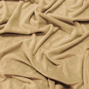May include: A close-up of a soft, beige fabric with a smooth, velvety texture. The fabric is draped and folded, creating a luxurious and cozy feel.