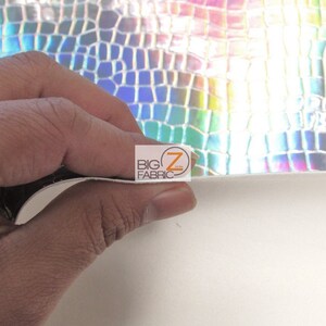 May include: A close-up of iridescent, silver faux leather with a crocodile pattern. The leather is flexible and has a slight sheen.