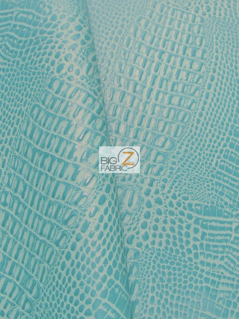 Op de afbeelding: Close-up van turquoise faux krokodillen ge&euml;mbost stof. De stof heeft een textuur, schubbige patroon.