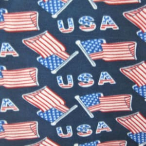 May include: Navy blue fleece fabric with a repeating pattern of American flags and the word "USA".
