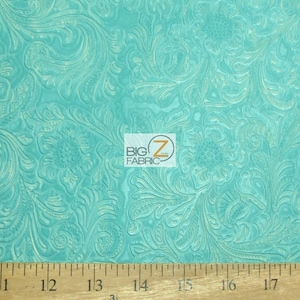 May include: Turquoise blue fabric with an embossed floral pattern. The fabric is textured and has a subtle sheen. A ruler is included for scale, showing the fabric is 17 inches wide.