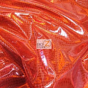 May include: Orange iridescent fabric with a crocodile skin pattern. The fabric is shiny and has a textured surface.