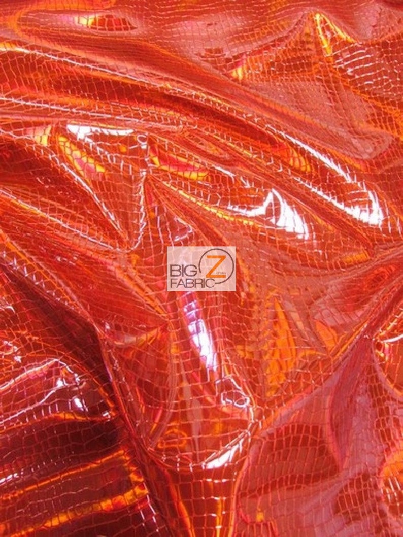 May include: Orange iridescent fabric with a crocodile skin pattern. The fabric is shiny and has a textured surface.