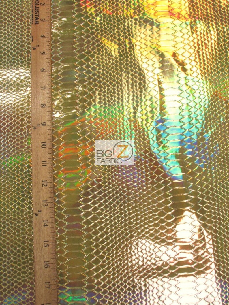 Pu&ograve; includere: Tessuto effetto pelle di serpente dorato iridescente con un motivo testurizzato. Il tessuto &egrave; misurato con un righello in pollici.