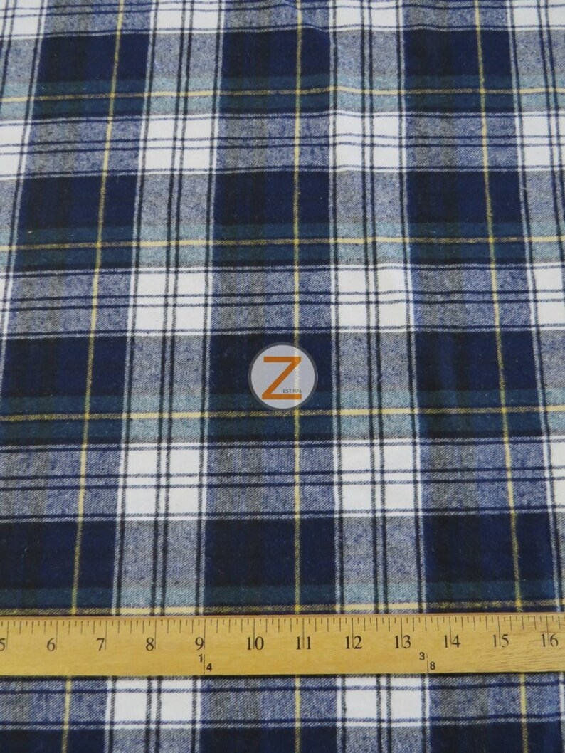 May include: A close-up of a blue and white plaid fabric with thin yellow stripes. The fabric is measured with a ruler in inches.