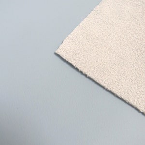 May include: A close-up of a white, textured fabric. The fabric is soft and fluffy, and it has a slightly bumpy texture.