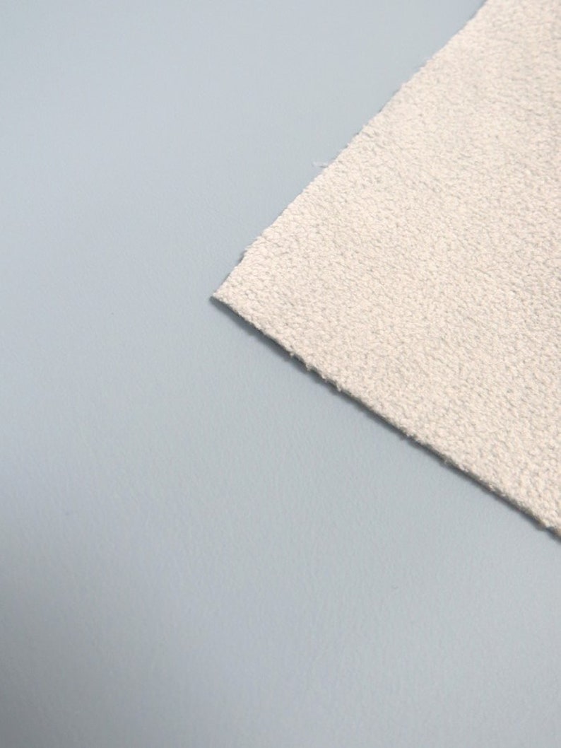 May include: A close-up of a white, textured fabric. The fabric is soft and fluffy, and it has a slightly bumpy texture.