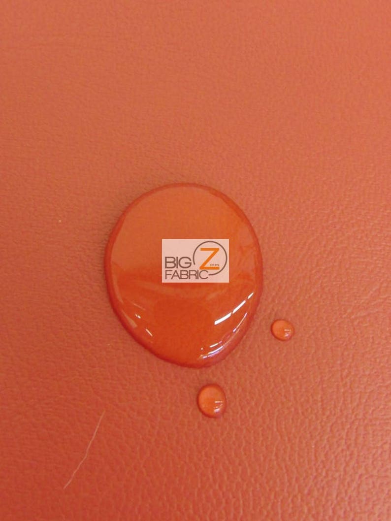 May include: A close-up of a bright orange fabric with a water droplet on it. The fabric has a textured surface. The water droplet is round and clear. The text "BIG Z FABRIC" is visible in the water droplet.