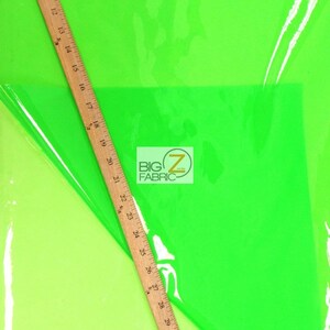Puede incluir: Tela verde ne&oacute;n brillante con una regla de madera en diagonal. La regla mide hasta 81 cm. La tela tiene un aspecto brillante y transparente. El logotipo "BIG Z FABRIC" es visible.