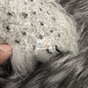 Może przedstawiać: Zbliżenie na czarną i białą tkaninę z imitacji futra o kr&oacute;tkim włosiu. Tkanina ma subtelny wz&oacute;r czarnych kropek na białym tle. Tkanina jest oznaczona etykietą "BIG Z FABRIC".