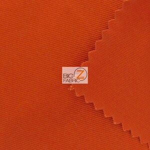 May include: Close-up of a bright orange fabric with a textured weave. The fabric is folded over on itself, creating a diagonal line.