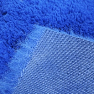May include: Close-up of a blue fuzzy rug with a woven backing. The rug is soft and plush, and the backing is made of a durable material.
