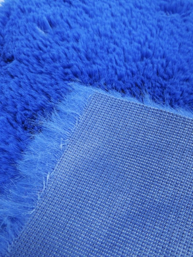May include: Close-up of a blue fuzzy rug with a woven backing. The rug is soft and plush, and the backing is made of a durable material.