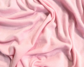 Puede incluir: Tela suave y rosa con una textura suave y aterciopelada. La tela está drapeada y doblada, creando una sensación de lujo y comodidad.