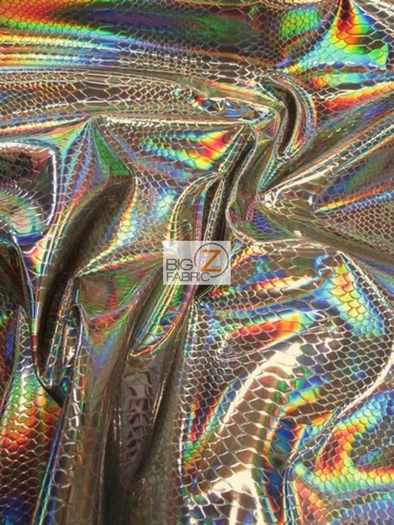 Pu&ograve; includere: Primo piano di un tessuto olografico iridescente con un motivo a pelle di serpente. Il tessuto ha un riflesso arcobaleno con sfumature di blu, verde, rosso e oro.