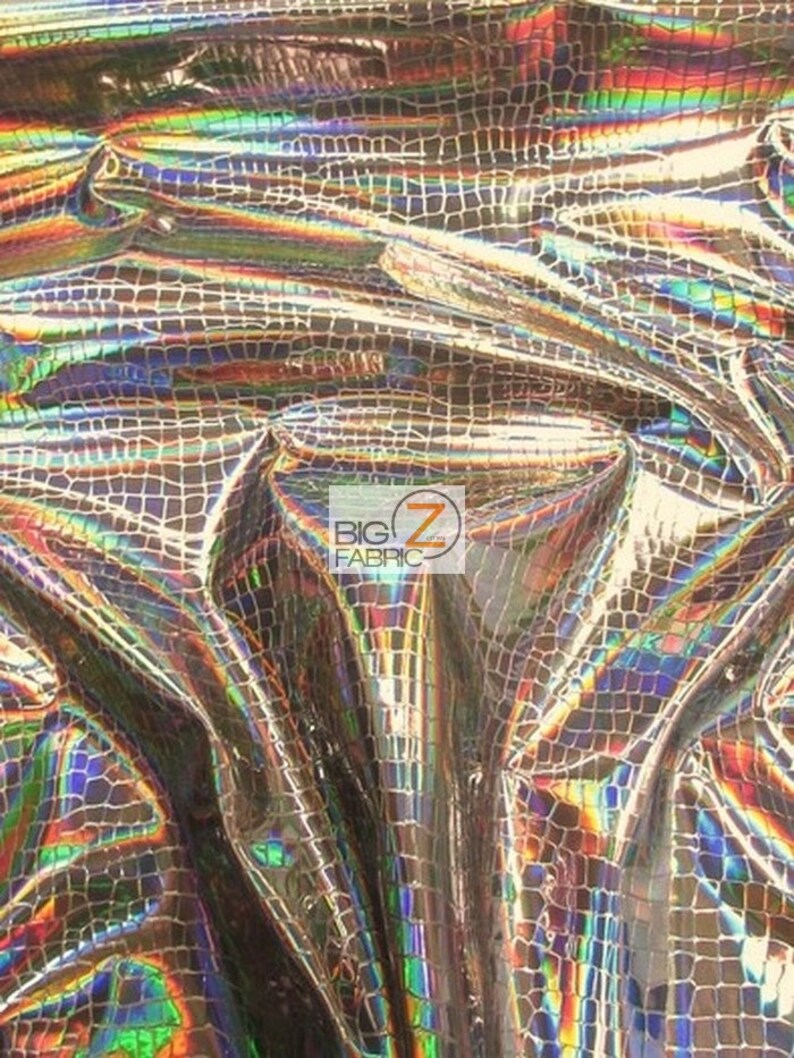 May include: A close-up of iridescent fabric with a crocodile skin pattern. The fabric has a shimmering, holographic effect with shades of gold, blue, green, and purple.