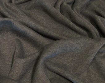 Puede incluir: Primer plano de una tela gris oscuro con una superficie suave y texturizada. La tela está doblada y drapeada, mostrando su caída y textura.