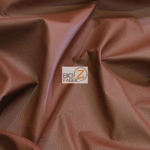 May include: Close-up of a brown faux leather fabric with a textured surface. The fabric is folded and draped, showing its texture and drape.