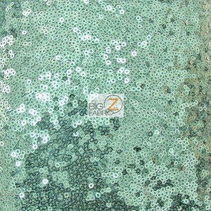 Op de afbeelding: Een close-up van tealgroene stof bedekt met pailletten. De pailletten zijn klein en rond en creëren een glinsterend effect.