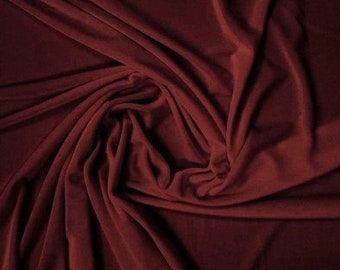 Puede incluir: Primer plano de una tela de color burdeos intenso con una textura suave y lisa. La tela está drapeada y doblada, creando un aspecto lujoso y elegante.