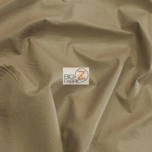 May include: A close-up of a light brown faux leather fabric with a textured surface. The fabric is folded and draped, showing its texture and drape.