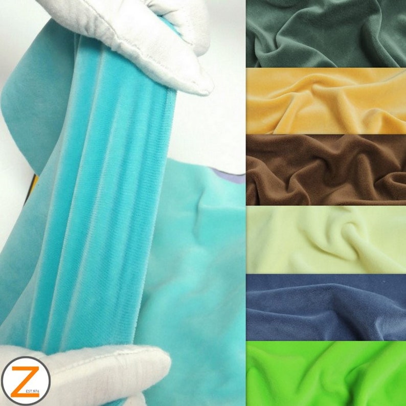 May include: A selection of colourful velvet fabric swatches in various shades, including teal, green, yellow, brown, and blue. The image also shows a close-up of a teal velvet fabric being held by a person wearing white gloves.