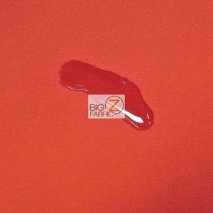 May include: A close-up of a bright orange fabric with a water droplet on it. The fabric is smooth and has a slight sheen. The water droplet is clear and round. The text "BIG Z FABRIC" is visible in the lower center of the image.