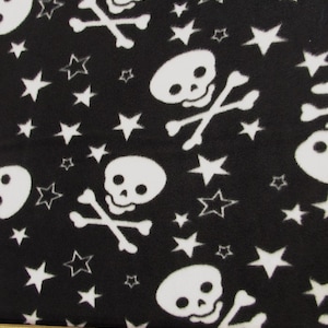 May include: Black fabric with a white skull and crossbones pattern and white stars. The fabric is measured with a ruler.