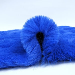 May include: A close-up of a bright blue faux fur fabric. The fabric is folded in half, showing the soft texture of the fur.
