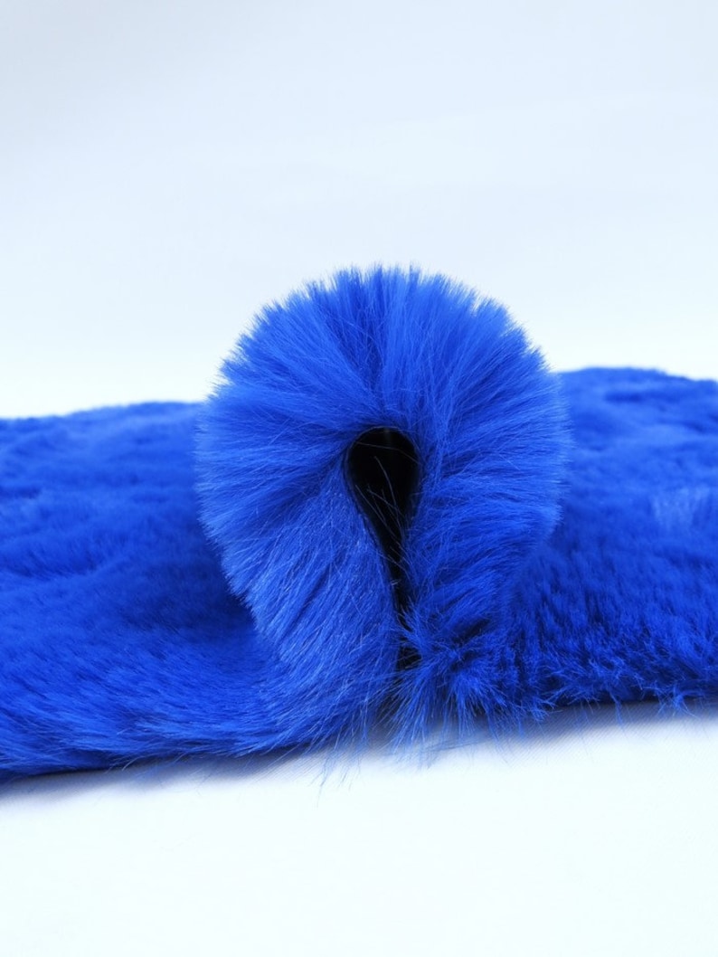 May include: A close-up of a bright blue faux fur fabric. The fabric is folded in half, showing the soft texture of the fur.
