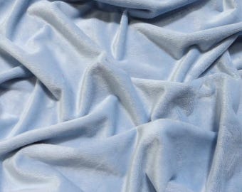 May include: A close-up of a soft, light blue fabric with a smooth, velvety texture. The fabric is folded and draped, creating a luxurious and inviting look.